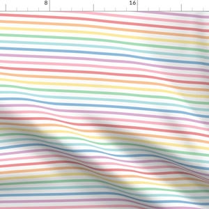 May include: A white fabric with thin, colourful stripes in a rainbow pattern. The stripes are pastel shades of red, orange, yellow, green, blue, indigo, and violet.