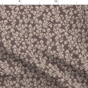May include: A fabric with a repeating floral pattern. The design features off-white flowers and stems against a dark brown background. The pattern is dense, creating a textured appearance. The fabric is suitable for various sewing projects.