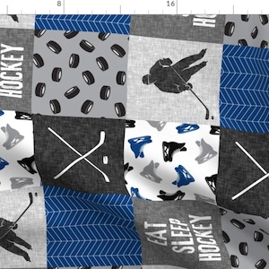 May include: A patchwork fabric design featuring a hockey theme. The fabric is made up of different squares with various hockey-related images, including hockey sticks, pucks, skates, and a hockey player. The fabric is in shades of grey, blue, and white. The text "Eat Sleep Hockey" is repeated on the fabric.