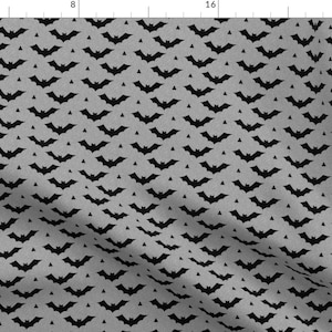 Puede incluir: Una tela gris con un patrón repetido de murciélagos negros. Los murciélagos están dispuestos en diagonal.