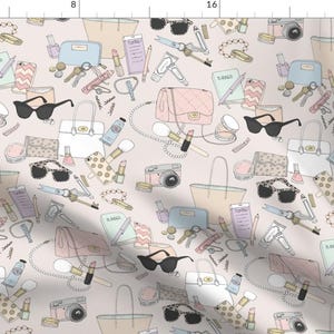 May include: A pink and white patterned fabric with a repeating design of purses, sunglasses, lipstick, cameras, and other accessories. The background is a light pink color.