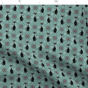 May include: A teal blue fabric with a repeating pattern of black cats and red and white starburst shapes.