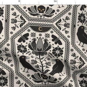 Può includere: Tessuto color crema con un motivo nero ripetuto di corvi, fiori, farfalle, teschi e lune crescenti. Il design ha un'estetica gotica o vittoriana, con un dettagliato stile punto croce.