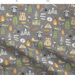 May include: A gray fabric with a repeating pattern of camping and woodland themed illustrations. The pattern includes raccoons, trees, tents, campfires, compasses, lanterns, and more. The text "Lake Crafts Camp" is repeated throughout the pattern.