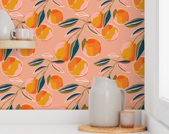 May include: A peach-colored wallpaper with a repeating pattern of orange fruit and green leaves. The wallpaper is shown in a kitchen setting with a white pitcher and a small jar on a wooden coaster.