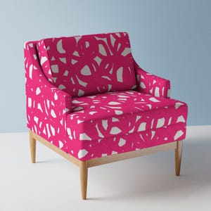 May include: A pink armchair with a white abstract pattern. The chair has a wooden frame and legs.