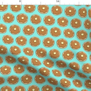 May include: A seamless pattern featuring a repeating design of brown pancakes with a pat of butter on top, set against a light blue background.