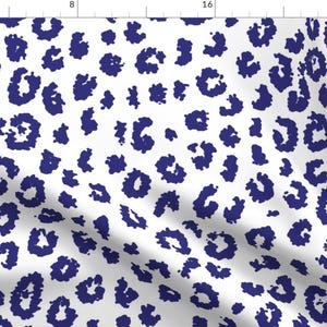 May include: White fabric with a repeating pattern of navy blue leopard spots. The spots vary in size and shape, creating a dynamic and textured appearance. This design is suitable for various fabric applications.