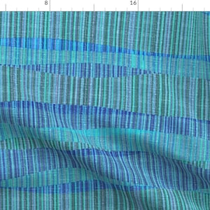 May include: Abstract patterned fabric with a blue, green, and turquoise color scheme. The fabric has a woven texture and a striped pattern.