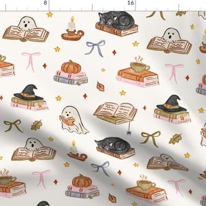 Puede incluir: Una tela de color crema con un patrón repetitivo de ilustraciones que incluye gatos negros durmiendo sobre libros, fantasmas blancos leyendo, tazas de té humeantes, velas encendidas en candelabros, calabazas, sombreros de bruja, lazos y estrellas amarillas.