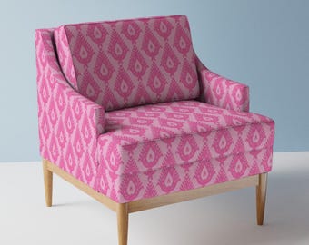 May include: A pink armchair with a geometric pattern upholstery and wooden legs.