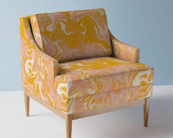 May include: A yellow and pink armchair with a marbled pattern. The chair has a wooden frame and legs.