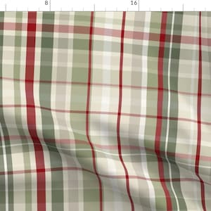 May include: A red, green and white plaid fabric with a subtle sheen. The fabric is folded and has a slight wrinkle.