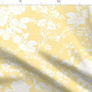 以下が含まれることがあります： 薄い黄色の背景に白い花の模様が施されたシームレスなパターン。パターンには、バラ、葉、つるが含まれています。