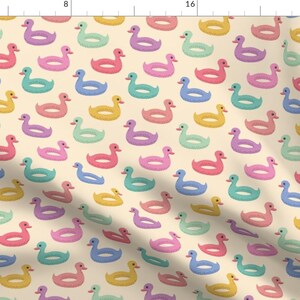 May include: A seamless pattern featuring a repeating design of pastel-colored inflatable duck rings on a cream background. The duck rings are in shades of yellow, pink, blue, green, and purple.