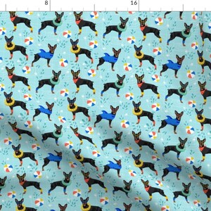 May include: A seamless pattern featuring black and brown dogs wearing colorful life preservers and playing with beach balls on a light blue background.