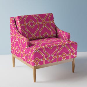 May include: A pink armchair with a geometric pattern in orange and white. The chair has a wooden frame and legs.