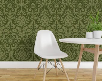 Könnte beinhalten: Ein weißer Stuhl aus geformtem Kunststoff mit vier hellen Holzbeinen und schwarzen Metallstreben, platziert neben einem weißen Tisch mit zwei kleinen grünen Topfpflanzen vor einer Wand mit einem olivgrünen Ananas-Damastmuster.