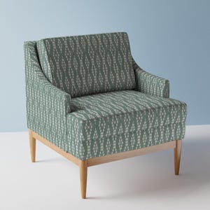 May include: A green armchair with a white and green geometric pattern upholstery. The chair has a wooden frame and legs.