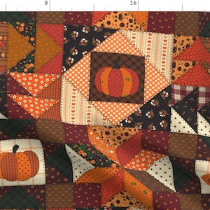 May include: A fabric featuring a patchwork quilt pattern with autumn-themed squares. The design includes orange pumpkins, brown, red, and dark green geometric shapes, floral prints, and checkered patterns. A ruler is visible along the top and left edges.