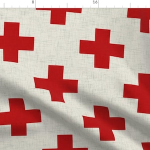 May include: A white fabric with a repeating pattern of red plus signs. The fabric has a subtle linen texture.