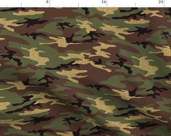 May include: A camouflage pattern fabric with a gold glitter overlay. The pattern features shades of green, brown, and black.