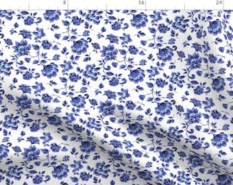 May include: White fabric adorned with a repeating pattern of blue floral designs. The pattern showcases diverse flower and leaf sizes, offering a classic and elegant aesthetic. Ideal for sewing and crafting projects, this fabric is versatile.