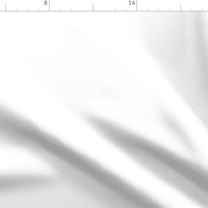 May include: A white fabric background with a smooth, flowing texture. The fabric is wrinkled and has a subtle sheen.