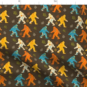 May include: A brown fabric with a repeating pattern of colourful Bigfoot figures. The Bigfoot figures are in shades of orange, yellow, blue, and white. The background is a dark brown.