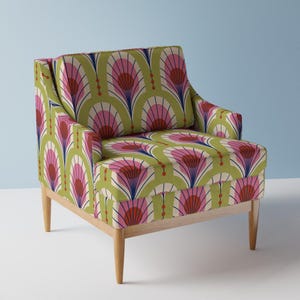 May include: A green armchair with a pink and blue geometric pattern. The chair has a wooden frame and legs.