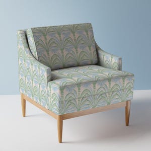 May include: An upholstered armchair featuring a repeating palm tree pattern in shades of light green and soft blue on a cream background. The chair has a square backrest, integrated armrests, and four tapered light-colored wooden legs.