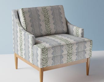 Puede incluir: Un sillón blanco con un patrón floral en tonos azules y verdes. El sillón tiene un marco y patas de madera.