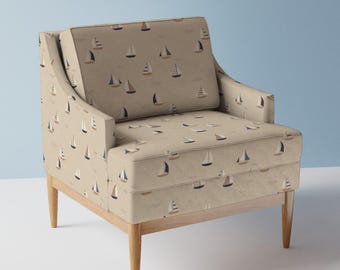 May include: A beige armchair with wooden legs features a fabric upholstery with a repeating pattern of small sailboats in shades of blue, brown, and beige.