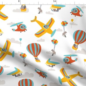 May include: A white background with a repeating pattern of yellow airplanes, red helicopters, hot air balloons with blue and orange stripes, and gray squirrels. The airplanes and helicopters have gray squirrels inside. The hot air balloons have gray squirrels in the baskets. The squirrels are all wearing aviator goggles.