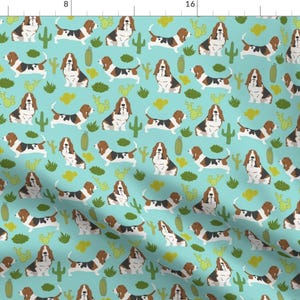 May include: A repeating pattern featuring basset hounds in a variety of poses, surrounded by cacti and green foliage. The background is a light blue color.