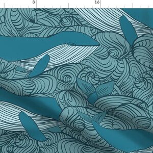May include: A teal blue fabric with a repeating pattern of stylized whales swimming in a sea of swirling lines. The whales are outlined in black and have a textured, striped pattern.