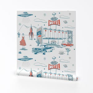 May include: Wallpaper roll with a retro illustration of a motel, cars, a woman, rockets, and UFOs. The design uses blue, red, and white, creating a vintage, mid-century aesthetic. The design is reminiscent of the 1950s.