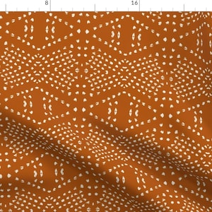 Op de afbeelding: Een naadloos patroon met een herhalend geometrisch ontwerp in de kleuren gebrand oranje en wit. Het patroon bestaat uit kleine witte stippen die in een cirkelvorm zijn gerangschikt.
