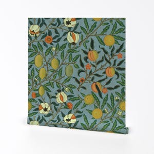 Puede incluir: Rollo de papel pintado con un patrón repetitivo de elementos frutales y florales. El diseño incluye limones, naranjas y granadas en tonos amarillos, naranjas y blancos, sobre un fondo azul apagado con follaje verde. El rollo está parcialmente desenrollado.