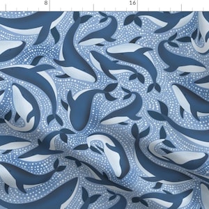 May include: A blue and white whale pattern fabric with a repeating design of whales swimming in a dotted pattern. The whales are a dark blue color and the background is a light blue color with white dots.