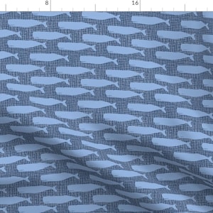 May include: A blue fabric with a repeating pattern of white whale silhouettes. The whales are stylized and resemble a simple, hand-drawn design.