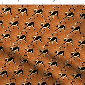 May include: A seamless pattern featuring black monkeys with white faces walking on a burnt orange background with stylized orange and white sunbursts.