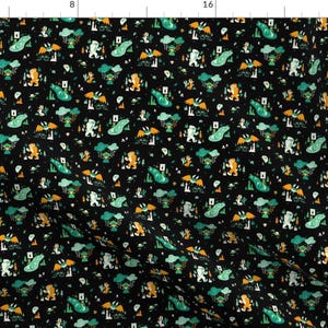 May include: A black fabric with a repeating pattern of green, yellow, and white illustrations of a creature with wings and a creature with a large foot. The pattern is on a black background.