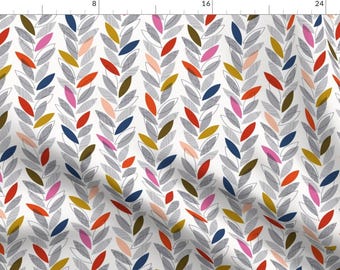 Op de afbeelding: Een witte stof met een herhalend patroon van gestileerde bladeren in tinten rood, roze, blauw, goud en grijs.