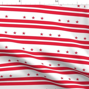 May include: Red and white striped fabric with red stars scattered throughout. The fabric is slightly wrinkled and has a soft, flowing texture.