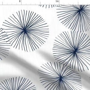May include: A white fabric with a repeating pattern of navy blue stylized sunbursts. The sunbursts are made up of thin lines radiating from a central point.