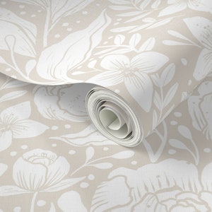 May include: A roll of wallpaper with a floral design. The pattern features large white flowers and leaves on a light beige backdrop. The wallpaper is partially unrolled, showcasing the repeating design.