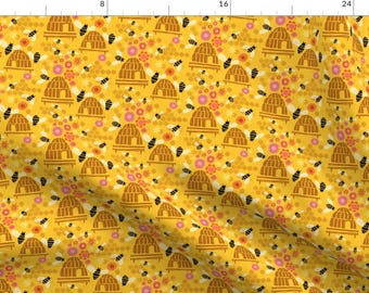 May include: A yellow fabric with a repeating pattern of beehives, bees, and flowers. The beehives are brown and have a simple design. The bees are black and yellow and the flowers are pink and yellow.