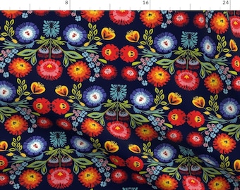 May include: A navy blue fabric with a repeating pattern of colorful flowers. The flowers are red, orange, yellow, blue, and green. The pattern is symmetrical and has a folk art style.