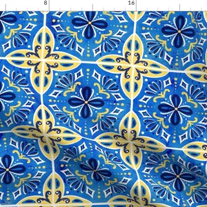 Op de afbeelding: Een naadloos patroon van blauwe, gele en witte tegels met een geometrisch ontwerp. De tegels hebben een aquareleffect en tonen een herhalend patroon van gestileerde bloemen en bladeren.